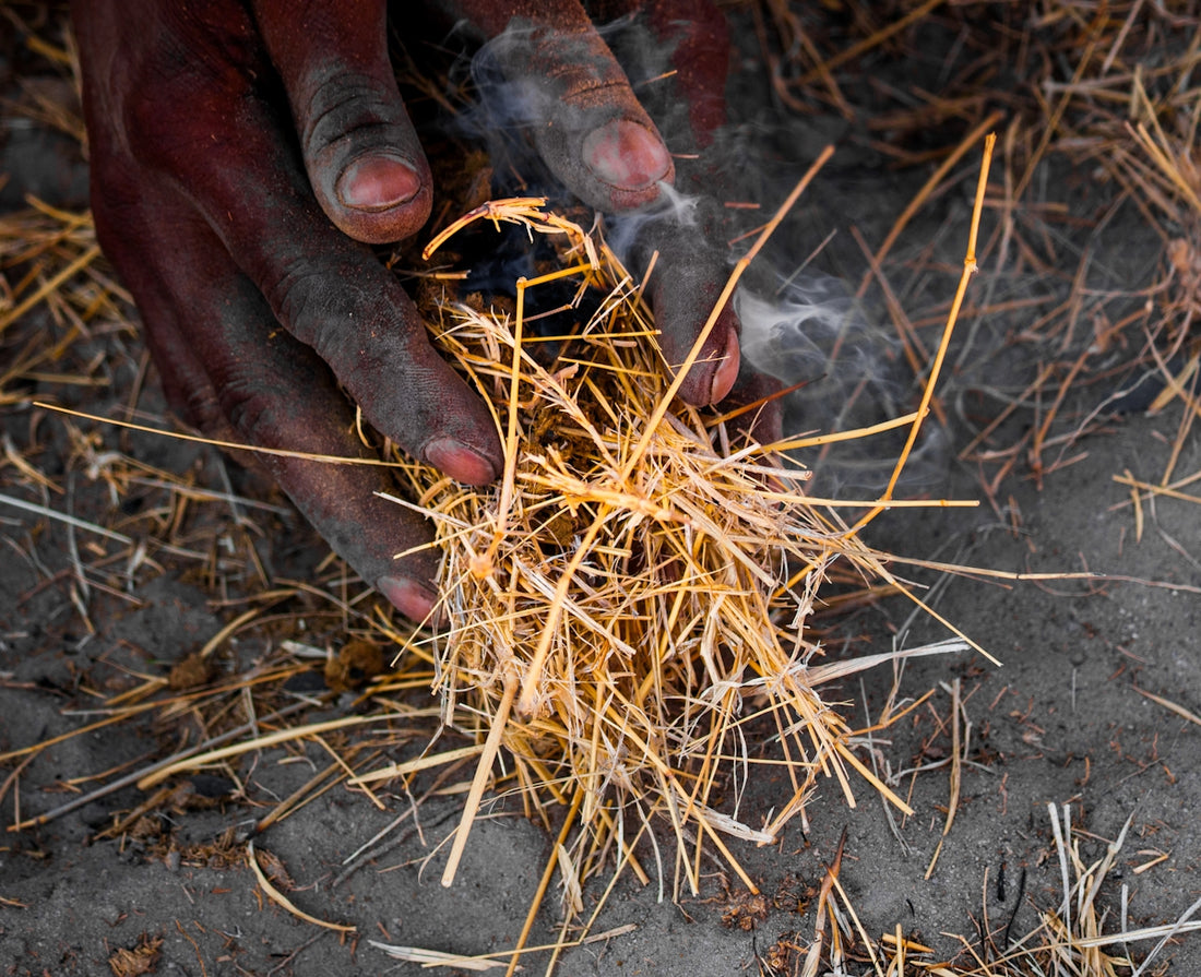 Hands starting a fire with dry grass