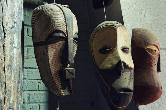 Three traditional wooden african masks hanging side by side.