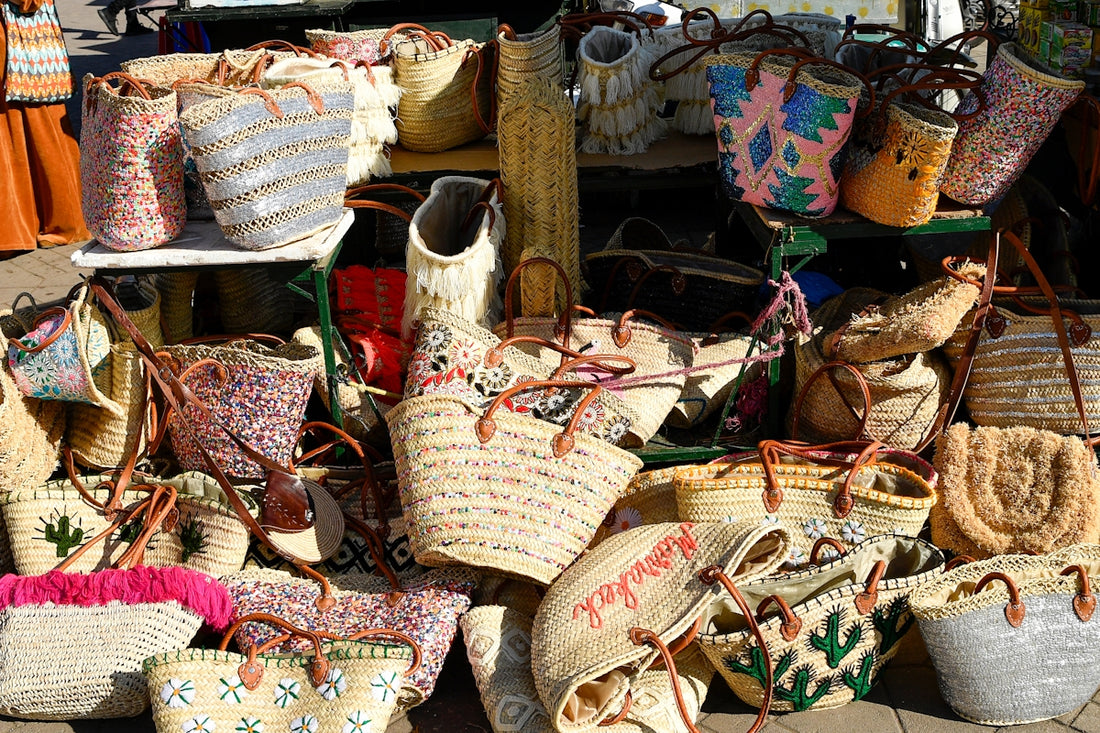 A display of many woven straw bags with colorful designs.