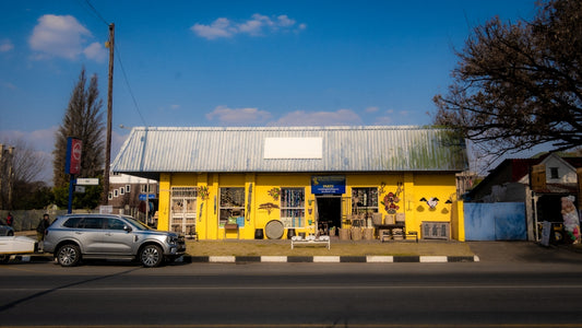 A bright yellow shop with a metal roof on a sunny street in Parys.